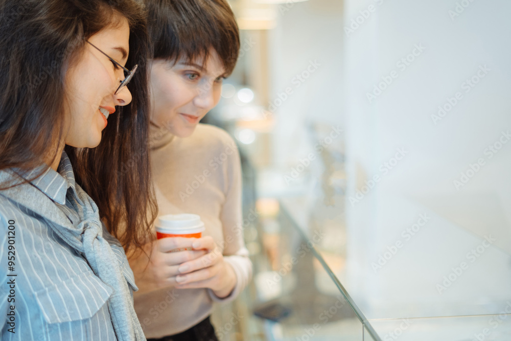 Two pretty girls choosing dessert from glass showcase in bakery shop Two pretty girls choosing dessert from glass showcase in bakery shop