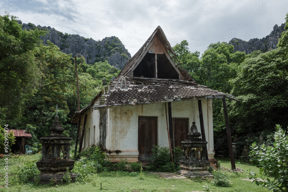 An old Buddhist temple nestled among lush greenery and dramatic mountains. The scene showcases two weathered stupas framing the entrance of the rustic temple. An old Buddhist temple nestled among lush greenery and dramatic mountains. The scene showcases two weathered stupas framing the entrance of the rustic temple.