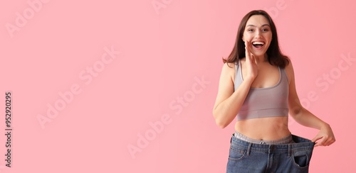 Foto Happy young woman in loose jeans on pink background with space for text