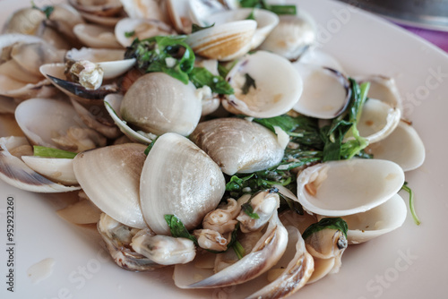 A close-up of a delicious dish featuring stir-fried clams garnished with fresh herbs.