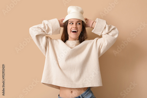 Young woman in winter clothes on beige background