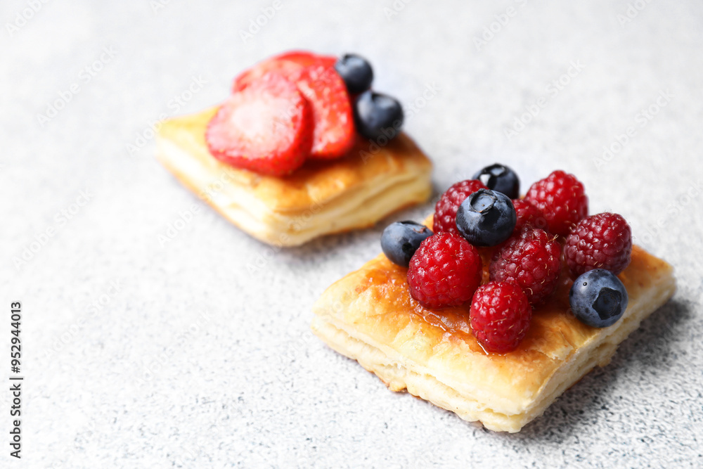 Tasty puff pastries with berries on light grey table, closeup. Space for text Tasty puff pastries with berries on light grey table, closeup. Space for text