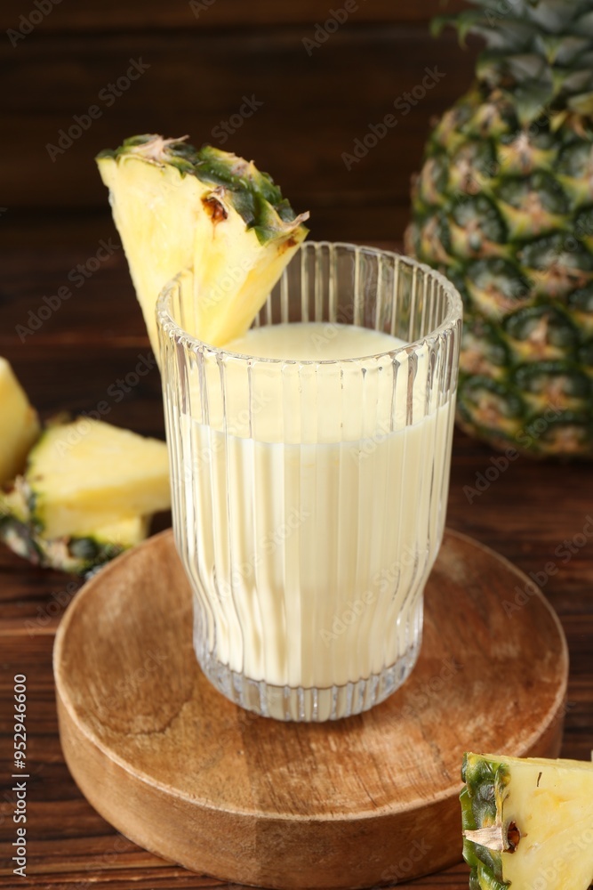 Tasty pineapple smoothie in glass and slices of fruit on wooden table, closeup Tasty pineapple smoothie in glass and slices of fruit on wooden table, closeup