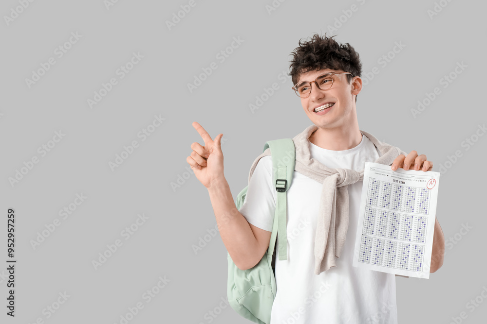 Happy male student with results of exam pointing at something on light background Happy male student with results of exam pointing at something on light background