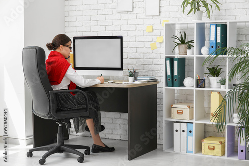 Female office worker talking on mobile phone at workplace in office