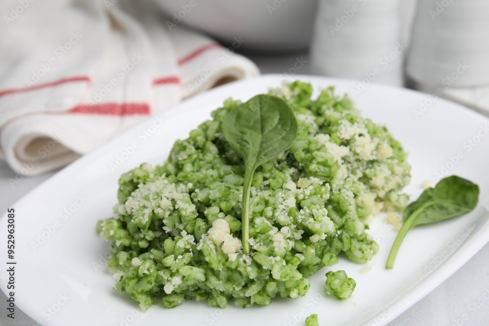 Delicious spinach risotto with parmesan cheese on white tiled table, closeup Delicious spinach risotto with parmesan cheese on white tiled table, closeup