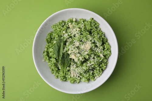 Delicious spinach risotto with parmesan cheese on light green background, top view