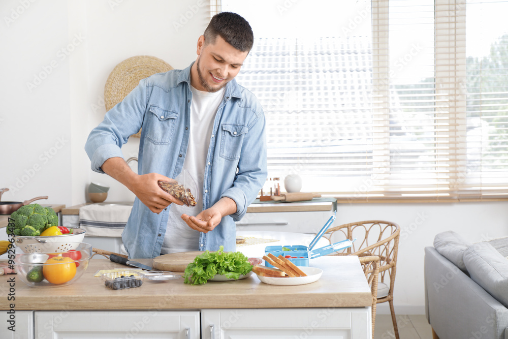 Young man with walnuts packing lunch box in kitchen Young man with walnuts packing lunch box in kitchen
