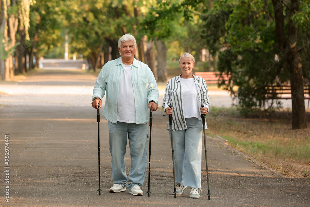 Mature woman and man with walking poles in park Mature woman and man with walking poles in park