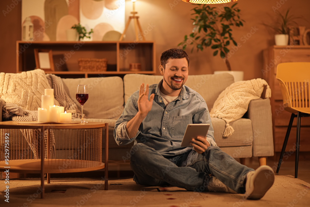 Fototapeta premium Handsome man with tablet computer having online date at home in evening
