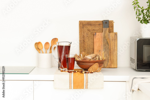 Jug and glass of tasty kvass with bread on table in kitchen photo