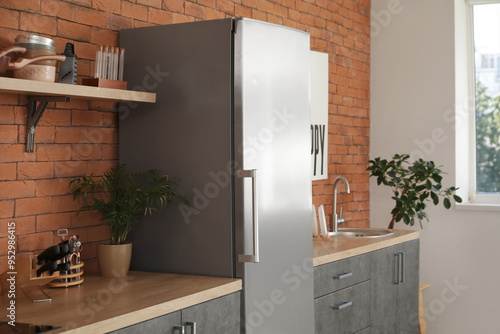 Interior of modern kitchen with silver fridge, counters and shelf photo