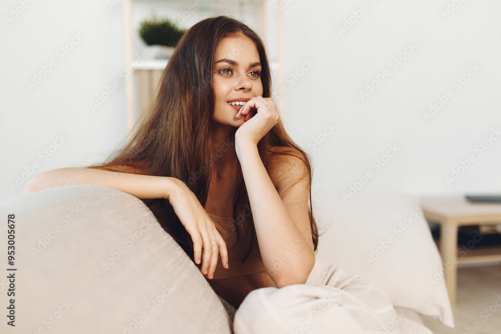 Happy Woman on Cozy White Sofa, Smiling and Looking at Camera in Modern Living Room Happy Woman on Cozy White Sofa, Smiling and Looking at Camera in Modern Living Room