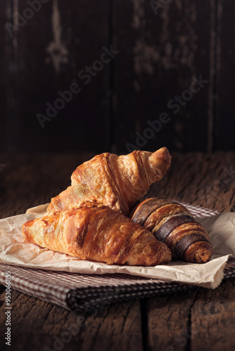 Croissants in Nuts Sugar, Butter, and Chocolate flavors arranged on a parchment paper with an antique wooden table for a classic look. photo