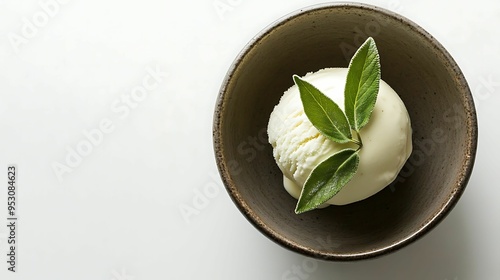 Minimalist presentation of vanilla ice cream topped with fresh sage leaves in a rustic ceramic bowl, set against a clean background.