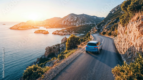 Fototapeta Naklejka Na Ścianę i Meble -  Blue car SUV is driving towards the sunset on a winding coastal road with scenic sea and mountain views