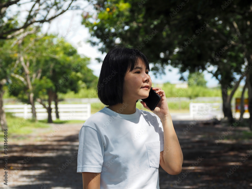 Asian businesswoman in white shirt walking and talking on the phone in public outdoor Asian businesswoman in white shirt walking and talking on the phone in public outdoor