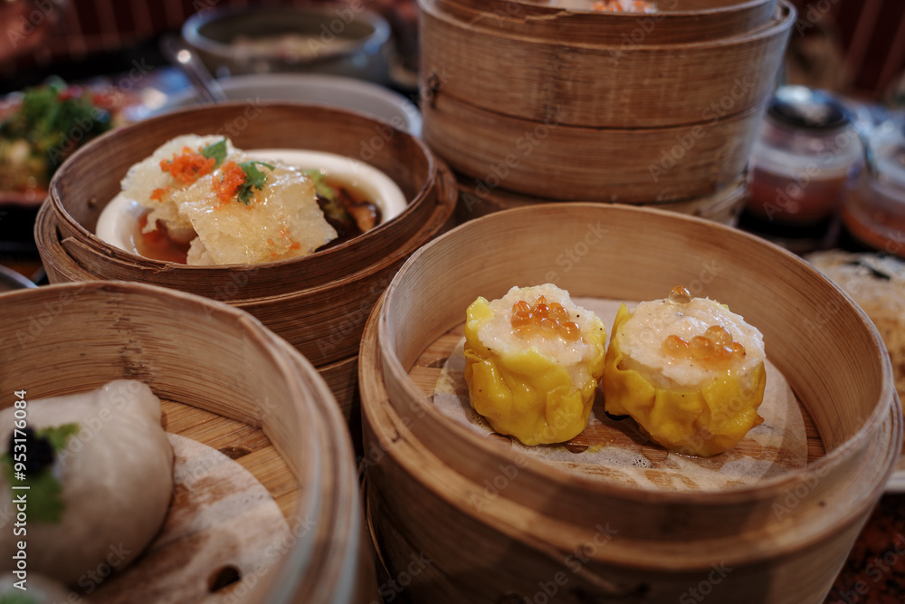 A close-up view of an assortment of dim sum dishes presented in traditional bamboo steamers. A close-up view of an assortment of dim sum dishes presented in traditional bamboo steamers.