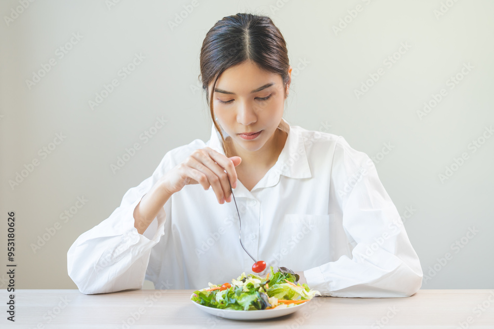 Diet in bored face, unhappy beautiful asian young woman, girl on dieting, holding fork at tomato on salad plate, dislike or tired with eat fresh vegetables. Nutrition of clean, healthy food good taste Diet in bored face, unhappy beautiful asian young woman, girl on dieting, holding fork at tomato on salad plate, dislike or tired with eat fresh vegetables. Nutrition of clean, healthy food good taste