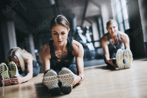 Stretching legs, exercise and women in gym for workout, training and warm up on floor for mobility. Fitness, friends and people for wellness, health and flexibility for performance or muscle strength