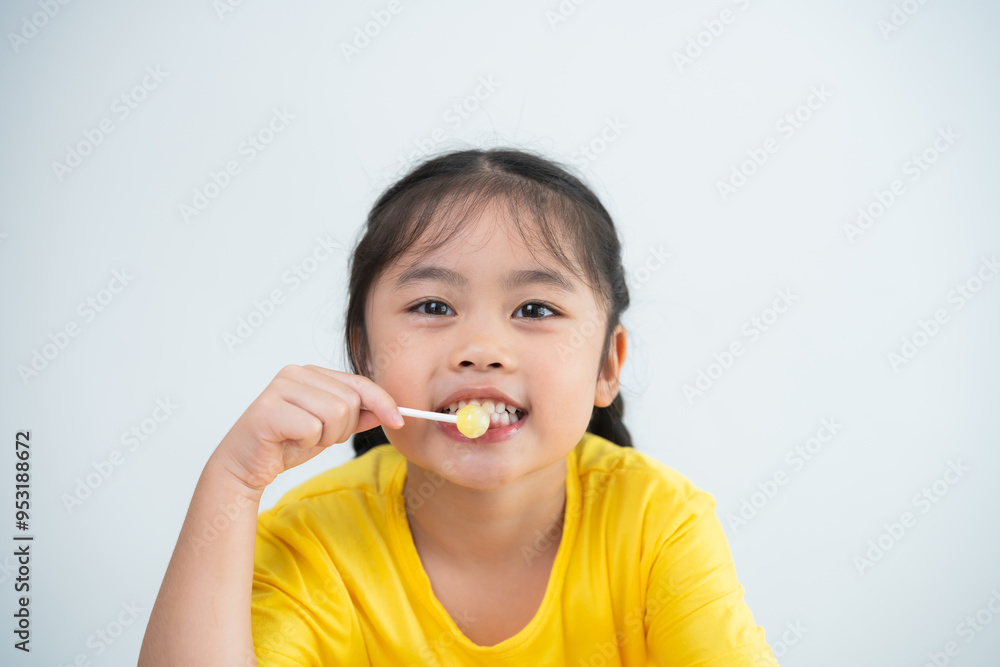Asian young girl is smiling while holding a toothbrush. She is wearing a yellow shirt. Concept of innocence and playfulness Asian young girl is smiling while holding a toothbrush. She is wearing a yellow shirt. Concept of innocence and playfulness
