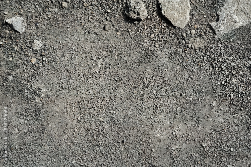 Textured surface of grey asphalt with scattered stones. Textured surface of grey asphalt with scattered stones.