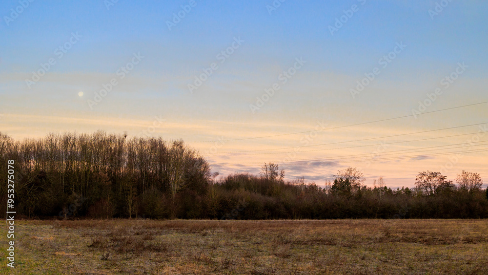 Slightly veiled full moon in the red sky above the houses of Siebenbrunn, the smallest district of the Fugger city of Augsburg