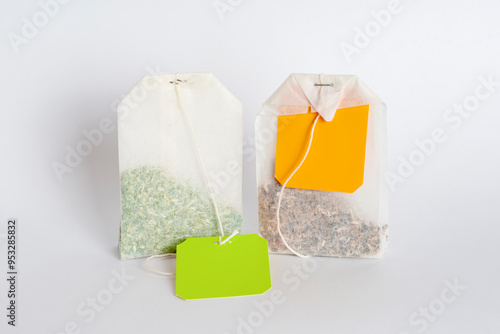 Two tea bags with empty labels of different colors on a white background. Template with blank tag on the theme of hot soft drinks.