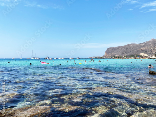 People enjoying the crystal clear sea at Burrone beach in the isle of Favignana. Aegadian Islands, Sicily, Italy.  photo