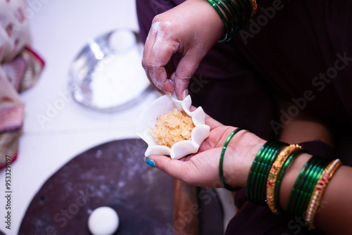 Woman making sweet rice modak stuffed with grated coconut and jaggery