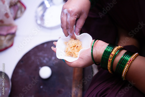 Woman making sweet rice modak stuffed with grated coconut and jaggery
