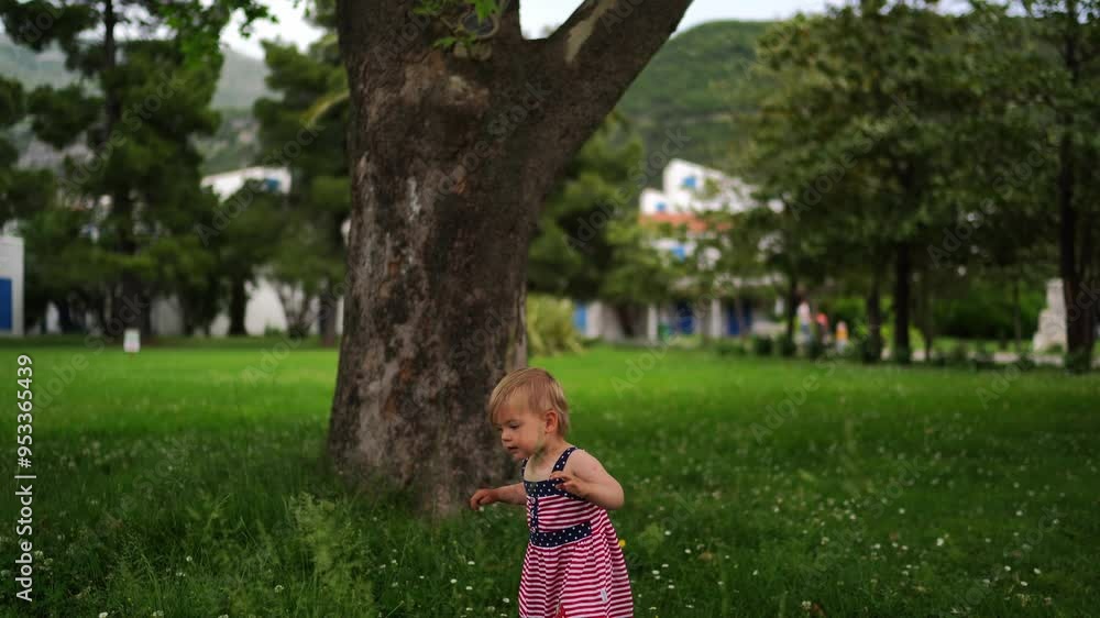 Little girl walks in a green meadow among the trees. High quality 4k footage Little girl walks in a green meadow among the trees. High quality 4k footage
