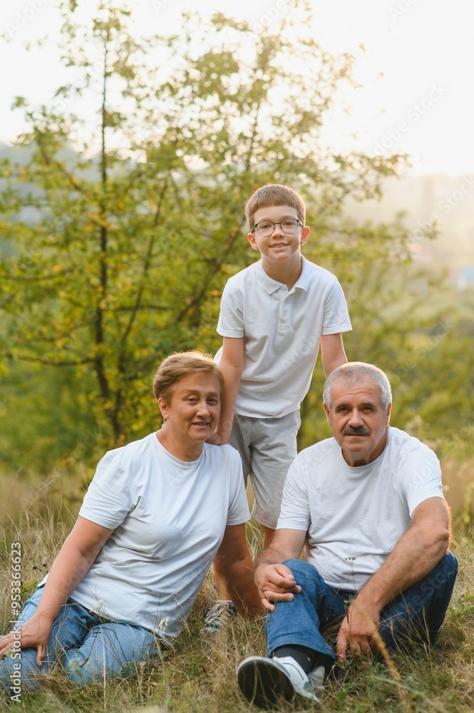 Fototapeta premium Grandparents with they grandson. They playing on meadow and joying in sunset