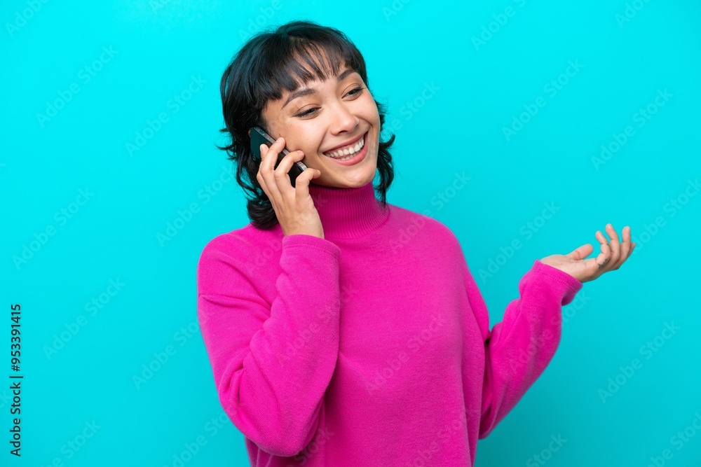 Young Argentinian woman isolated on blue background keeping a conversation with the mobile phone with someone Young Argentinian woman isolated on blue background keeping a conversation with the mobile phone with someone