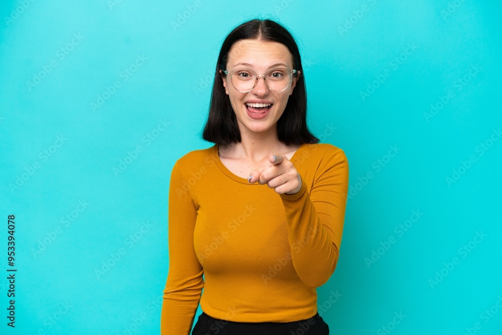 Young caucasian woman isolated on blue background surprised and pointing front