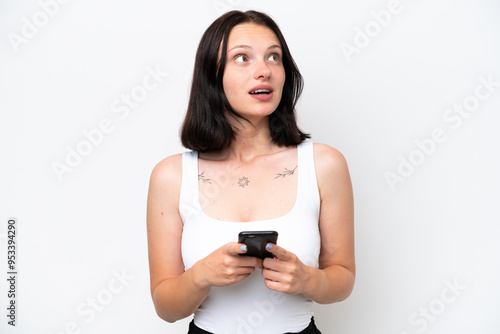 Young caucasian woman isolated on white background using mobile phone and looking up