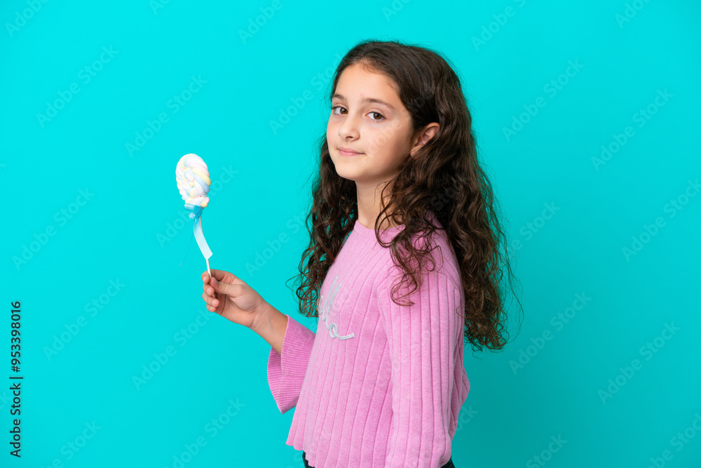Little caucasian girl holding a lollipop isolated on blue background smiling a lot Little caucasian girl holding a lollipop isolated on blue background smiling a lot