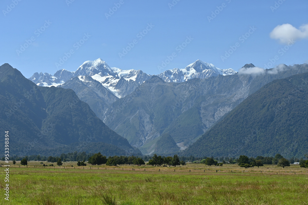 The view of Mt. Tasman near Mt. Cook from afar in a fresh sunny day under blue sky, West Coast, New Zealand. The view of Mt. Tasman near Mt. Cook from afar in a fresh sunny day under blue sky, West Coast, New Zealand.