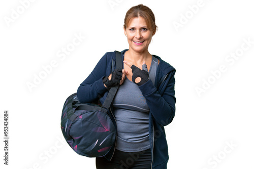 Middle-aged sport woman with sport bag over isolated background pointing to the side to present a product