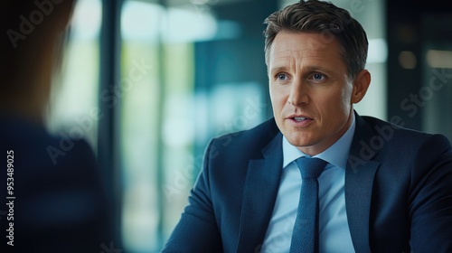 A businessman engaged in a serious discussion during an office meeting, with a modern, plant-filled workspace in the background, emphasizing a collaborative environment..