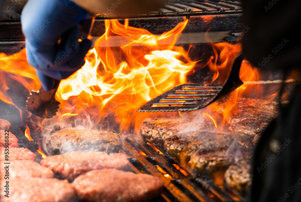 Cooking burgers on hot grill with flames - flame grilled barbeque style burger patties. Hamburgers are a traditional summer BBQ food. Cooking burgers on hot grill with flames - flame grilled barbeque style burger patties. Hamburgers are a traditional summer BBQ food.