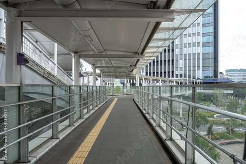Papier peint A long, covered pedestrian walkway or footbridge with glass railing connects to a modern building