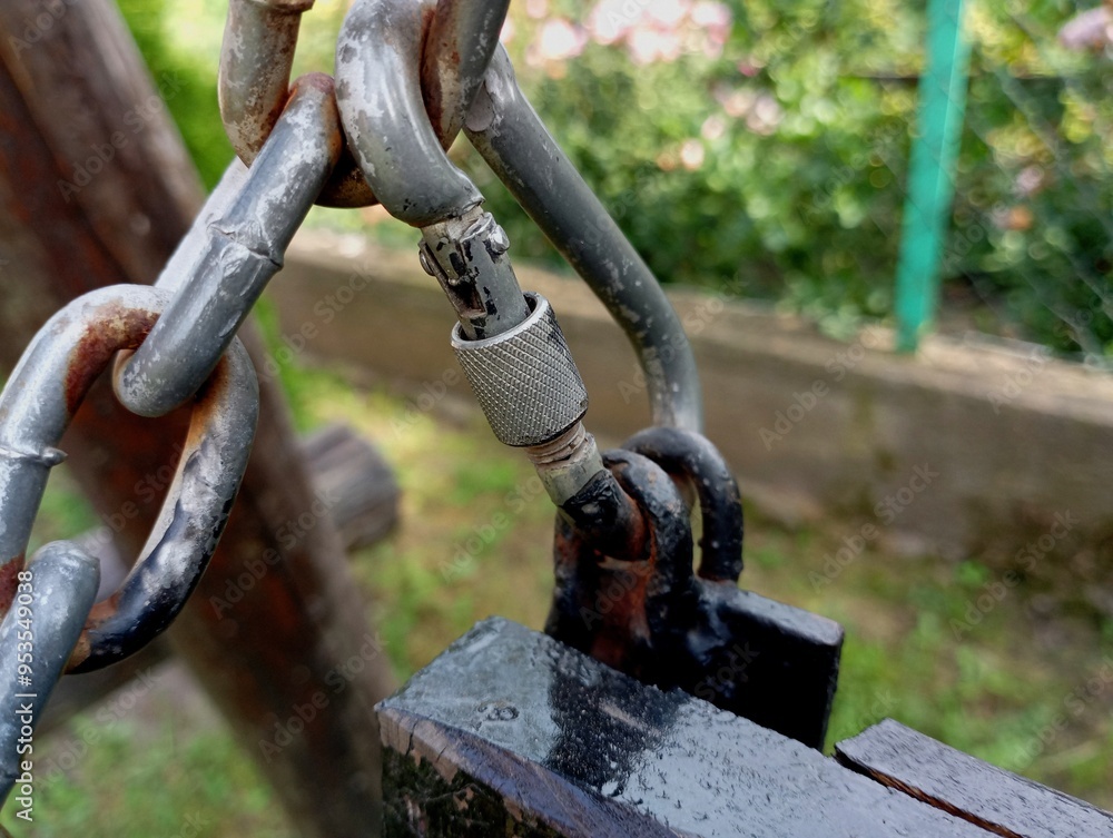 A strong steel carabiner to which the chain and the wooden structure of the swing are attached. Iron fastening of a wooden swing. A strong steel carabiner to which the chain and the wooden structure of the swing are attached. Iron fastening of a wooden swing.