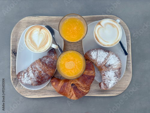 colazione con cappuccino, brioche e spremuta di arancia su vassoio, breakfast with cappuccino, brioche and orange juice on a tray photo