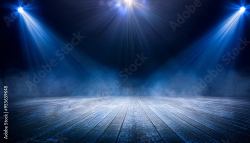 暗い舞台上に青いスポットライトが複数当たっているシーンを描いています。床には光が反射し、煙や霧が漂うことで幻想的で神秘的な雰囲気が強調されています。ステージの中心には集中して光が集まり、これから始まるパフォーマンスやイベントの期待感を高める構図です。generative AI