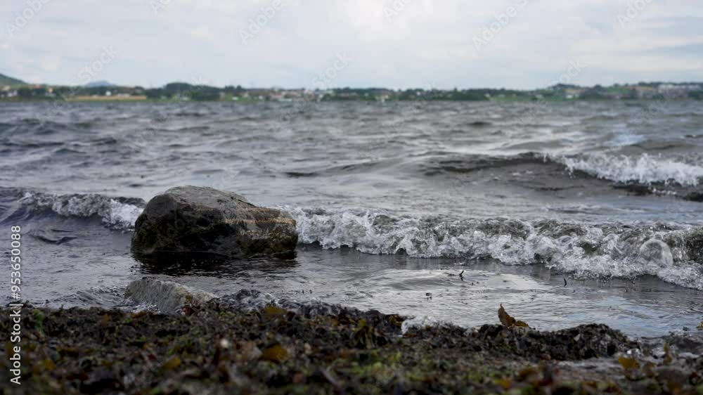Close up waves hitting small rock at coast in Norway
