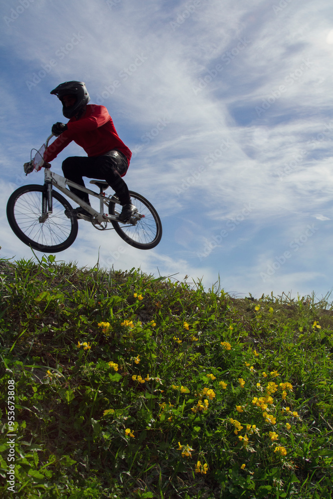 Obraz premium Low angle view of a silhouetted bmx racer against a cloudy sky.