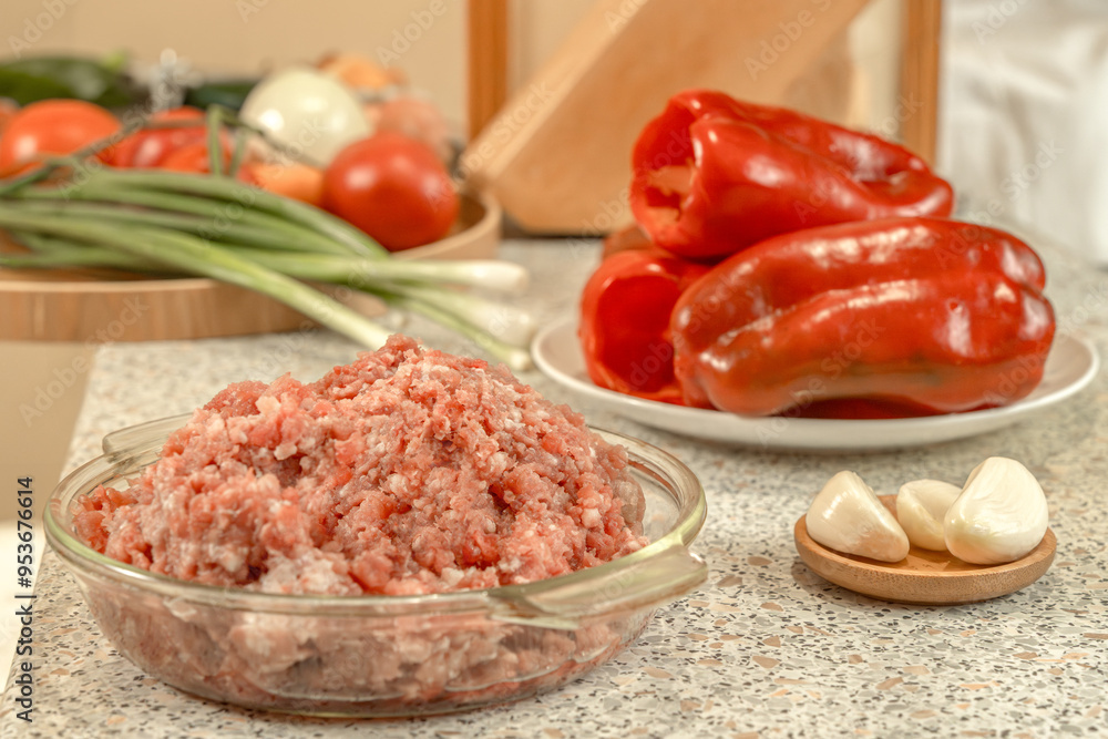 Raw minced meat against the background of peeled and prepared for stuffing red bell peppers and other vegetables. Raw minced meat against the background of peeled and prepared for stuffing red bell peppers and other vegetables.