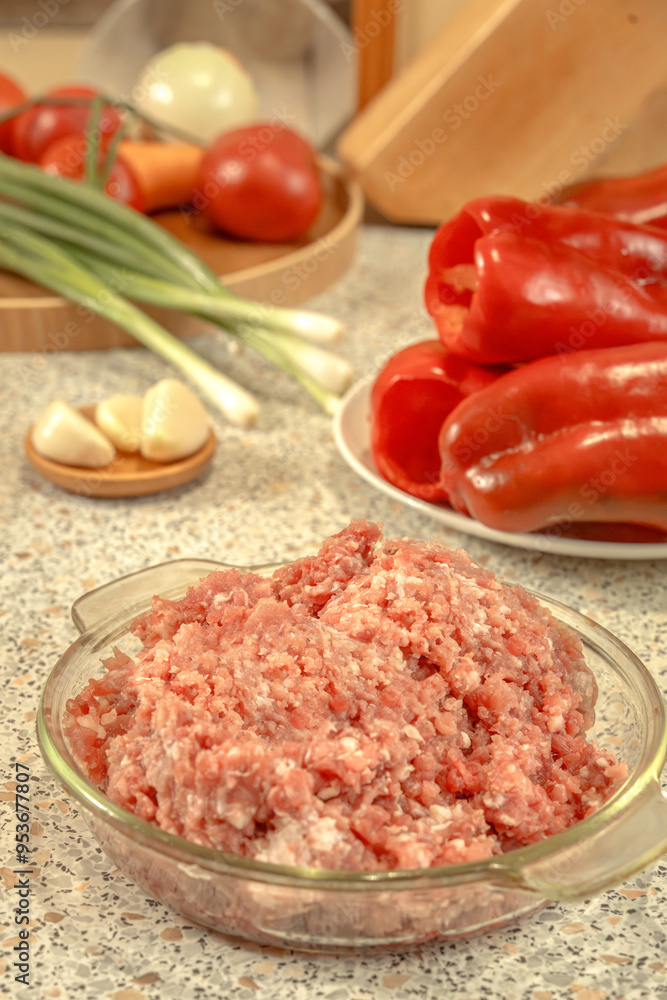 Raw minced meat against the background of peeled and prepared for stuffing red bell peppers and other vegetables. Raw minced meat against the background of peeled and prepared for stuffing red bell peppers and other vegetables.