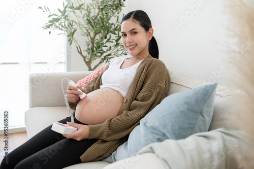 pregnant woman using pocket fetal doppler to listen baby heartbeat